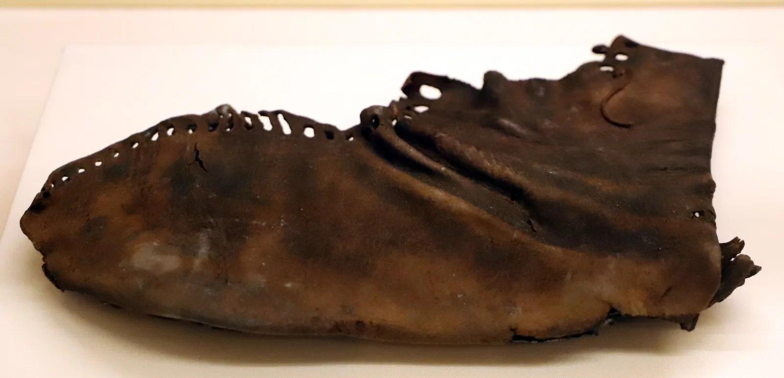 A flattened, dark-brown closed leather Roman boot, its lacing and stitching still visible.