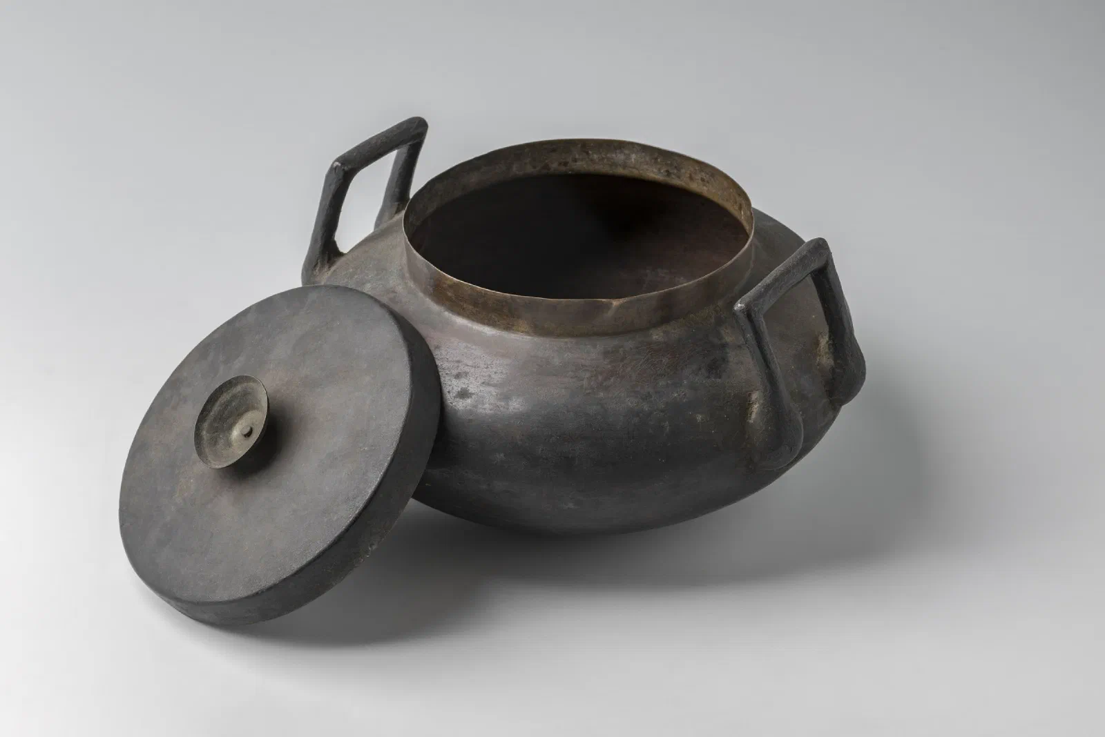 A round-bellied bronze cooking pot with a wide mouth and two small handles.