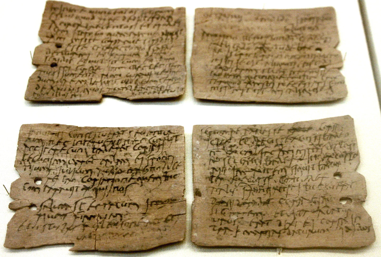A thin, cracked sliver of wood covered in faded lines of Latin cursive ink.