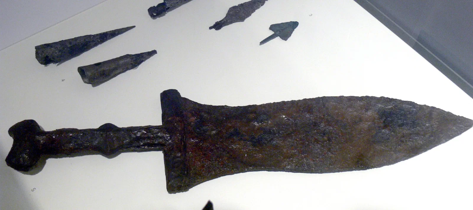 An ancient Roman dagger and its scabbard, the iron dark with age and the metal scabbard fittings still in place.